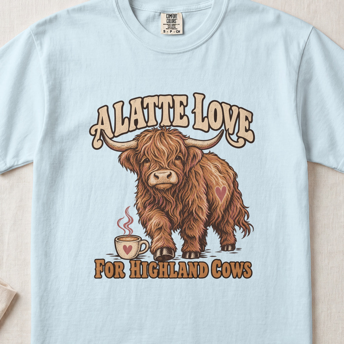 A Latte Love for Highland Cows Highland cow design on a Chambray Comfort Colors 1717 T-shirt, flat lay