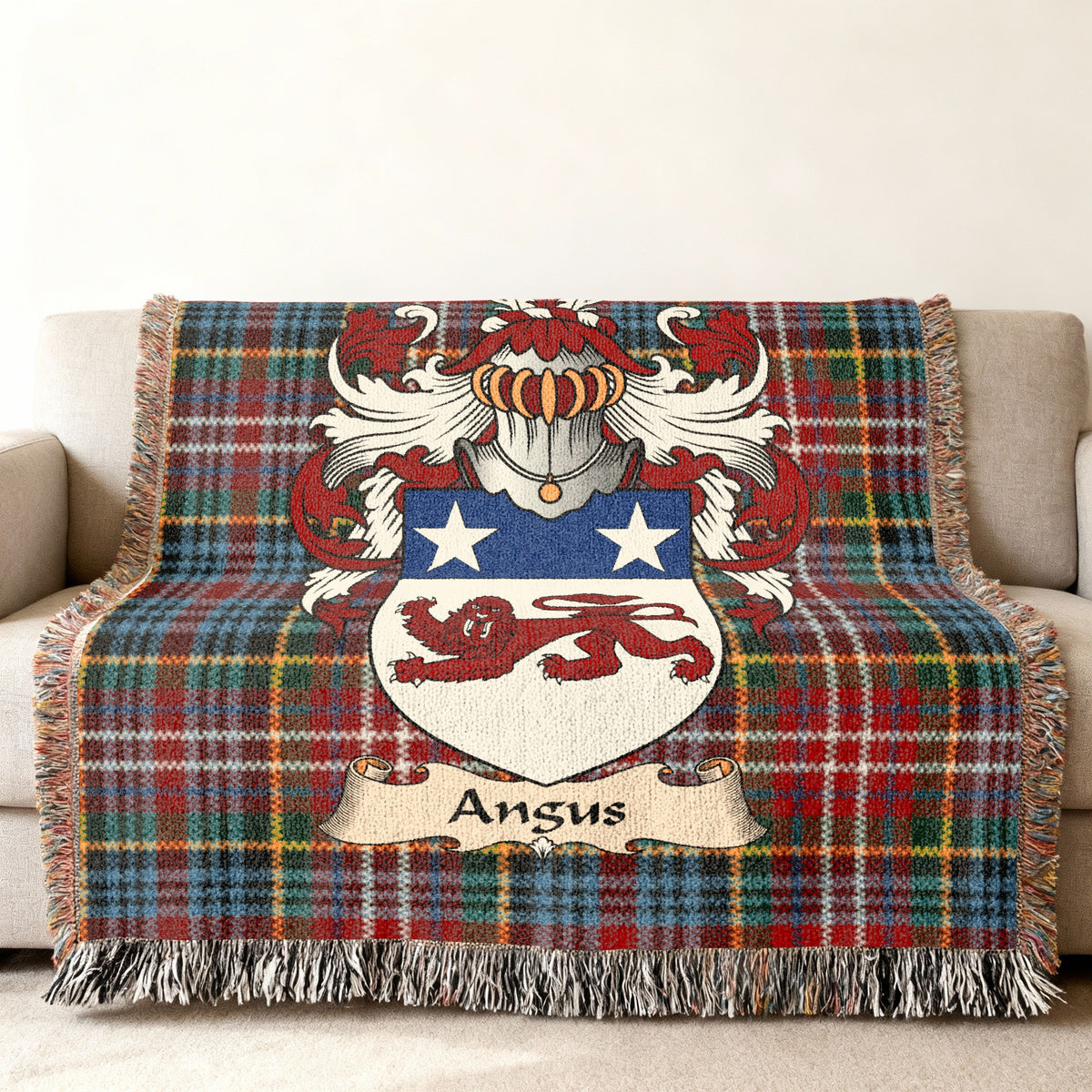 Angus Scottish family shield woven blanket with Caledonia tartan background on a sofa