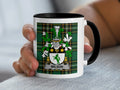 White mug with black rim featuring a green plaid background and the Wilson family crest.