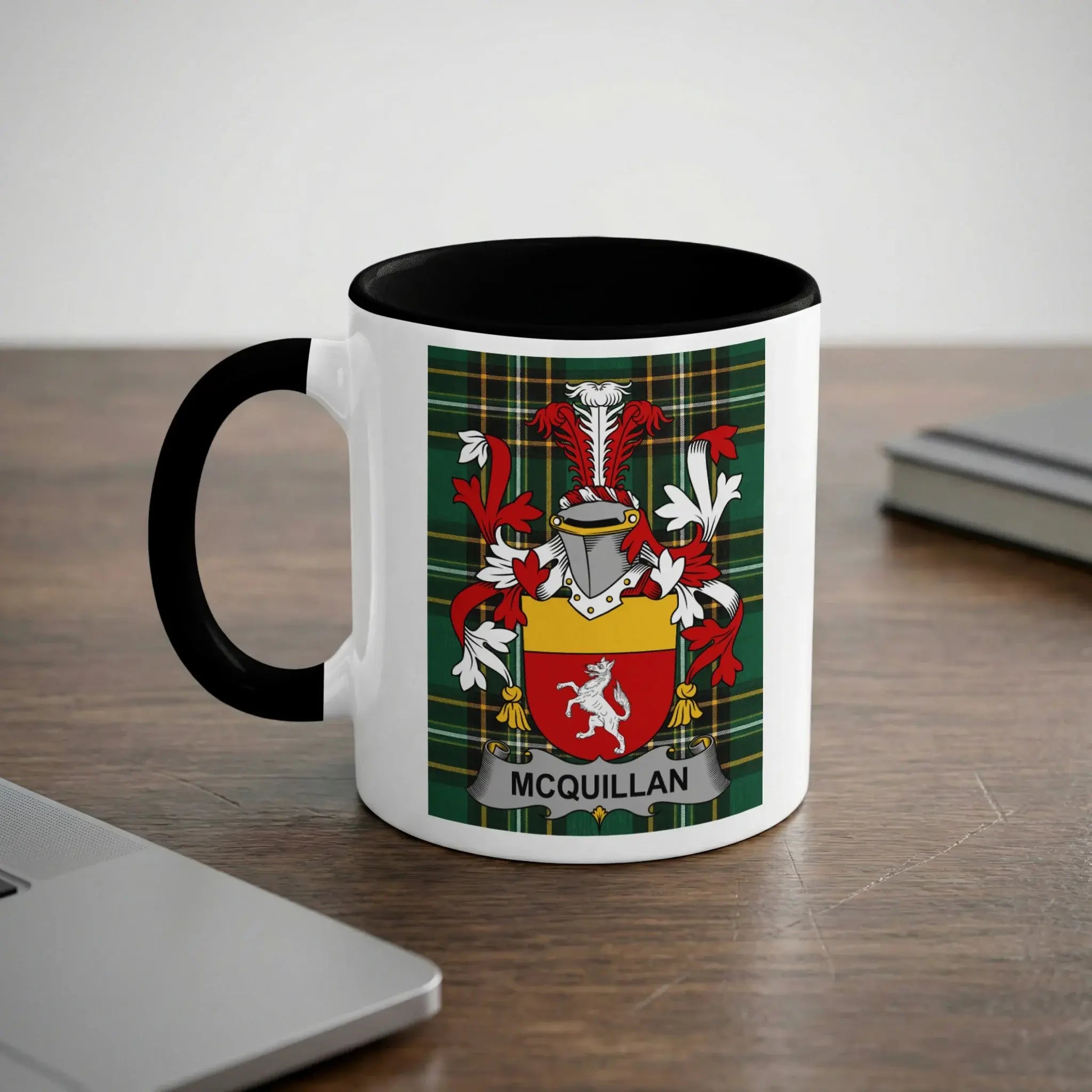 White mug with black handle and rim featuring a Scottish coat of arms with "MCQUILLAN" banner.