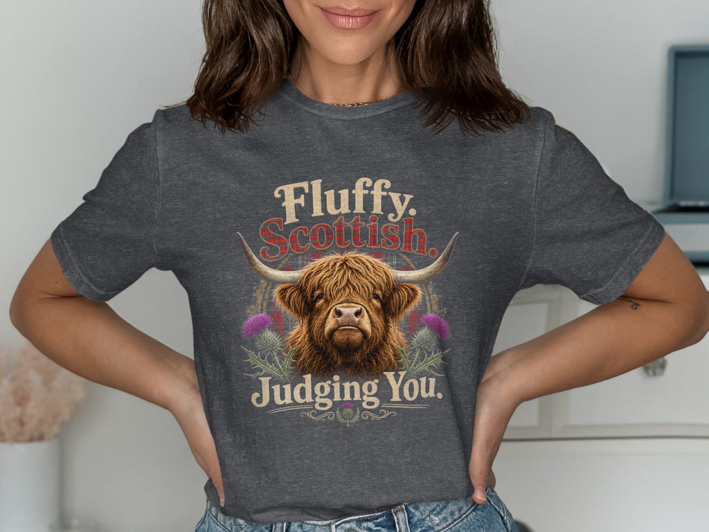 Highland cow graphic with text "Fluffy. Scottish. Judging You." on a dark grey t-shirt.