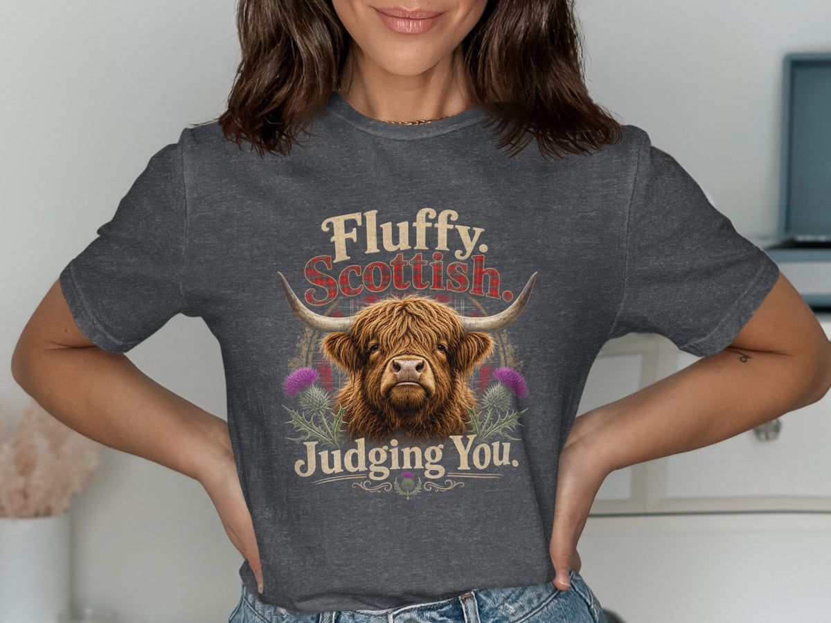 Highland cow graphic with text "Fluffy. Scottish. Judging You." on a dark grey t-shirt.