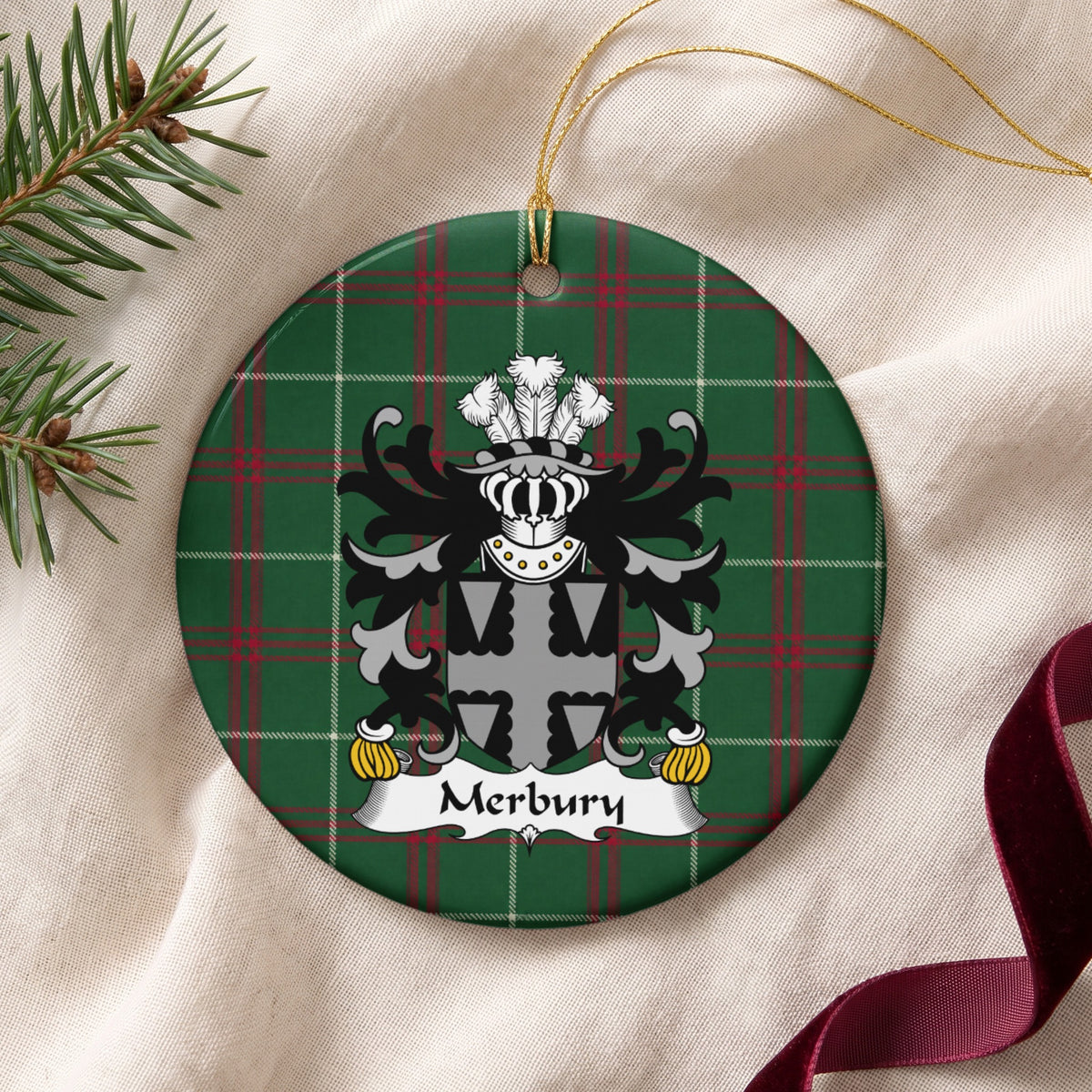 Merbury ornament on cream fabric with gold string, evergreen and burgundy ribbon; a gray-and-black shield with a scalloped cross pattern on Welsh National Tartan.