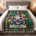 Tartan blanket with Ryder family crest, draped on a bed.