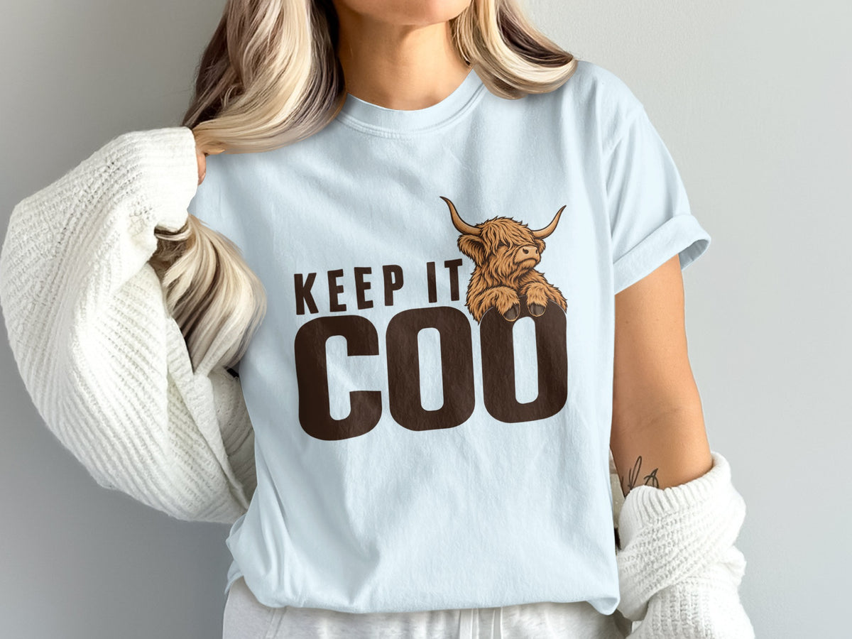 Model wearing the Keep It Coo Highland cow Comfort Colors T-shirt in Chambray