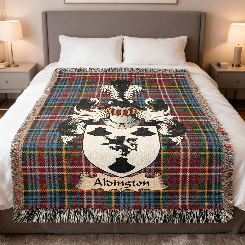 Alsington Scottish family crest woven blanket on a Caledonia tartan background, displayed on a bed
