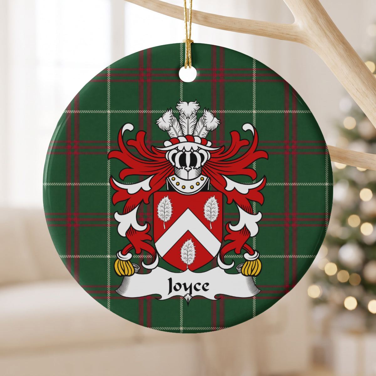 Joyce ornament hanging from a pale wooden branch; a white chevron and three white leaves on a red shield on Welsh national tartan.