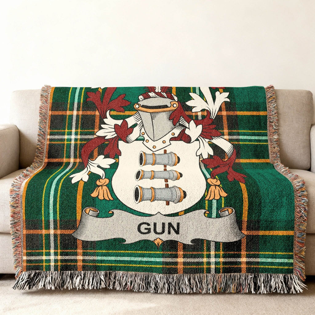 Green plaid blanket with a coat of arms featuring cannons and the name "GUN".