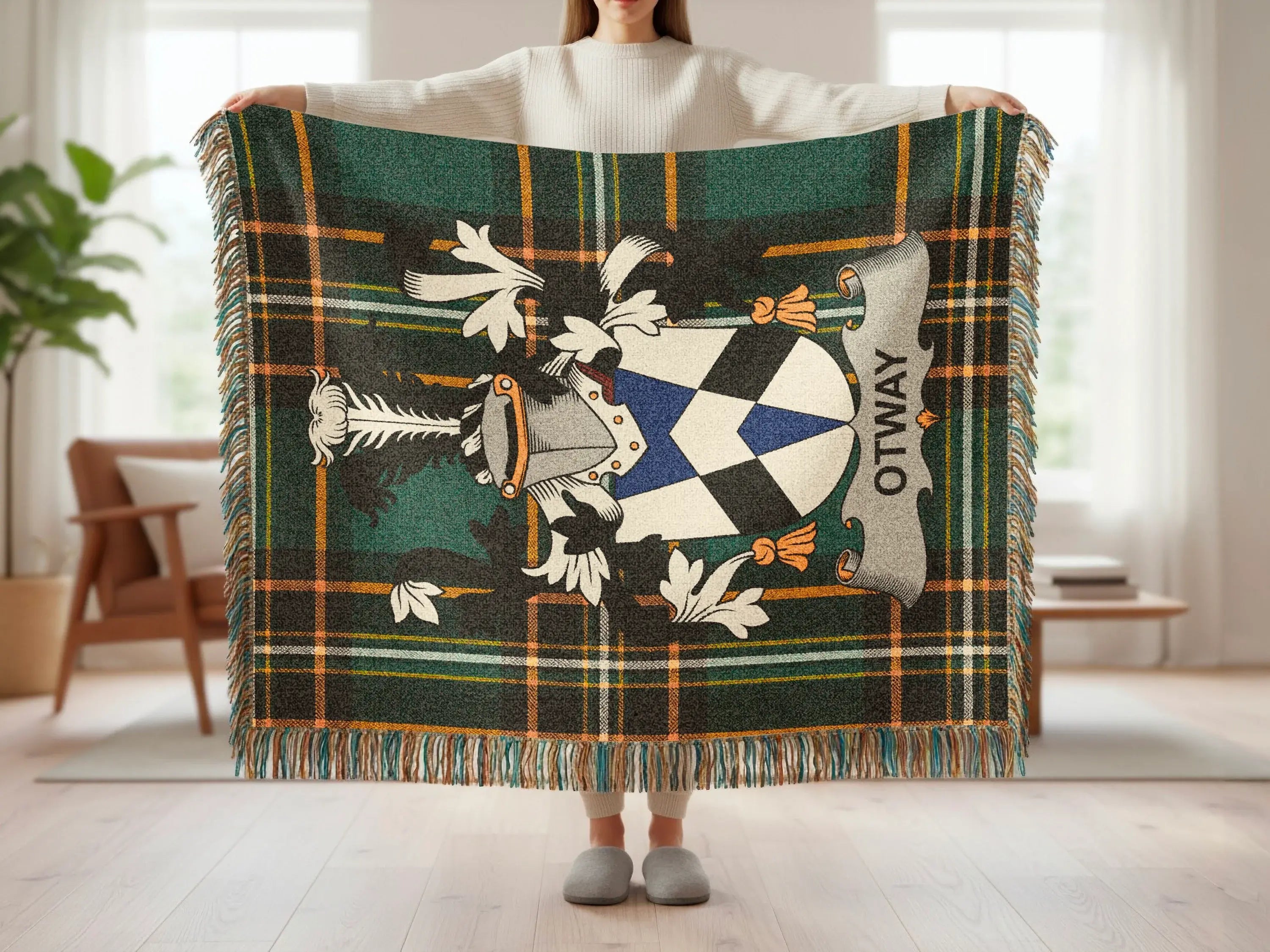 Green plaid blanket with Otway crest held up by person.
