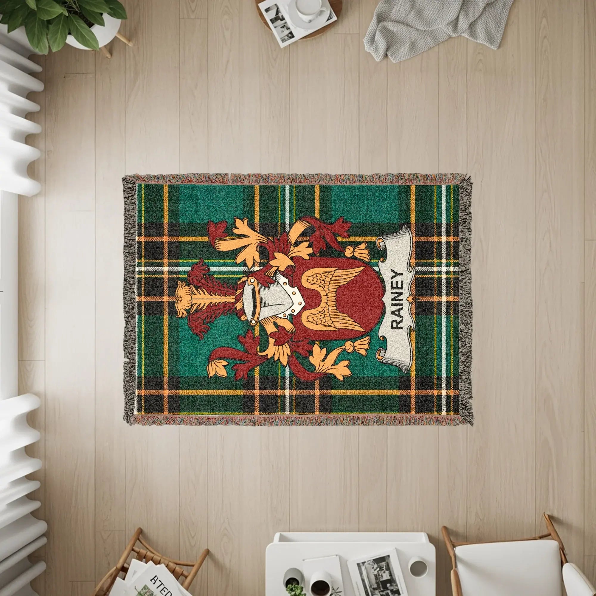 Woven throw blanket with green, yellow, and red plaid and the RAINEY family crest.