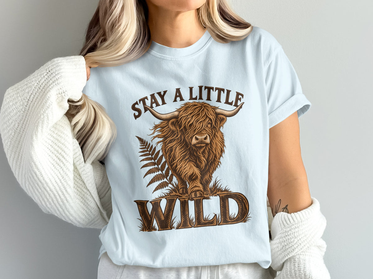 Model wearing the Stay a Little Wild Highland cow Comfort Colors T-shirt in Chambray