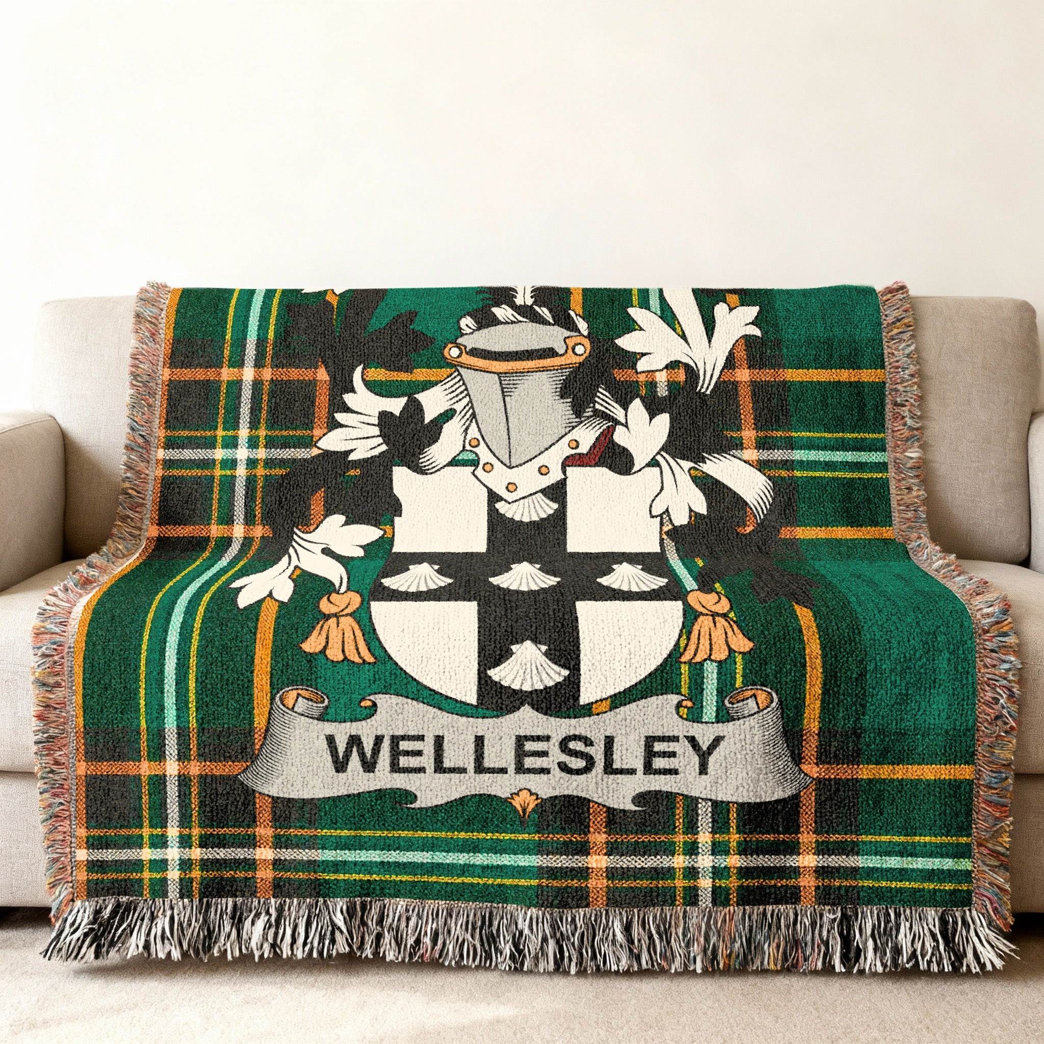 Wellesley tartan blanket with crest draped on a sofa.