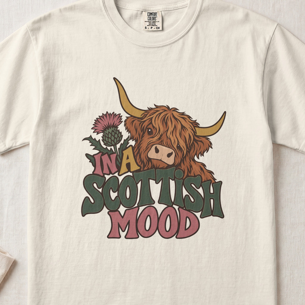 In a Scottish Mood Highland cow design on an Ivory Comfort Colors 1717 T-shirt, flat lay