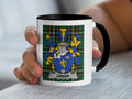 White mug with black rim featuring the Greer family crest on a plaid background.