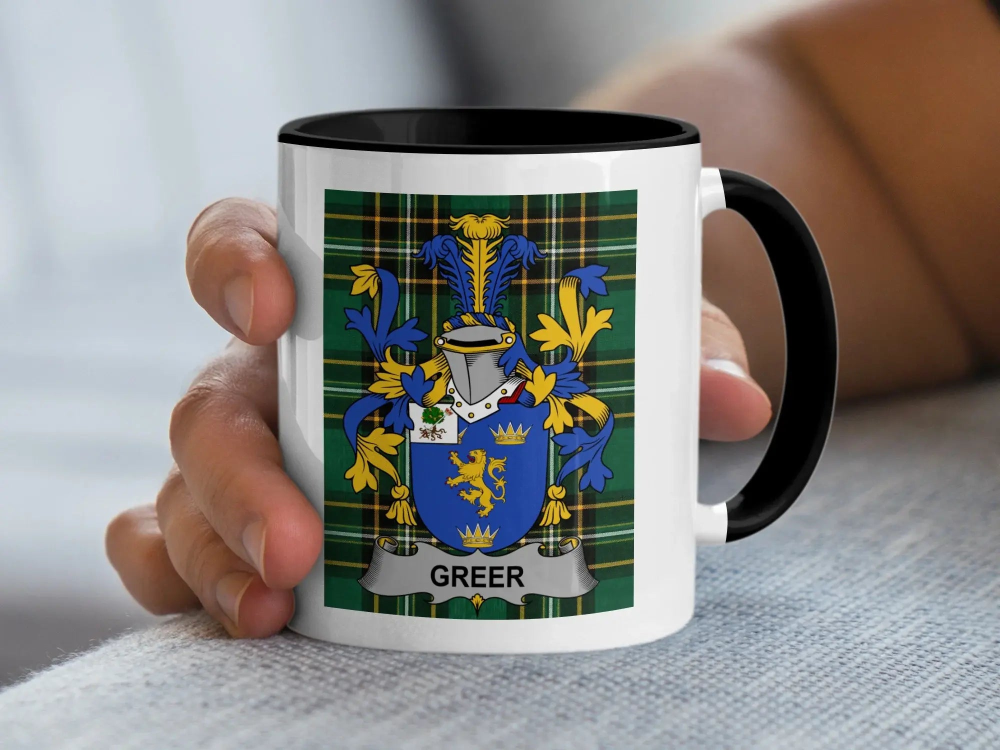 White mug with black rim featuring the Greer family crest on a plaid background.