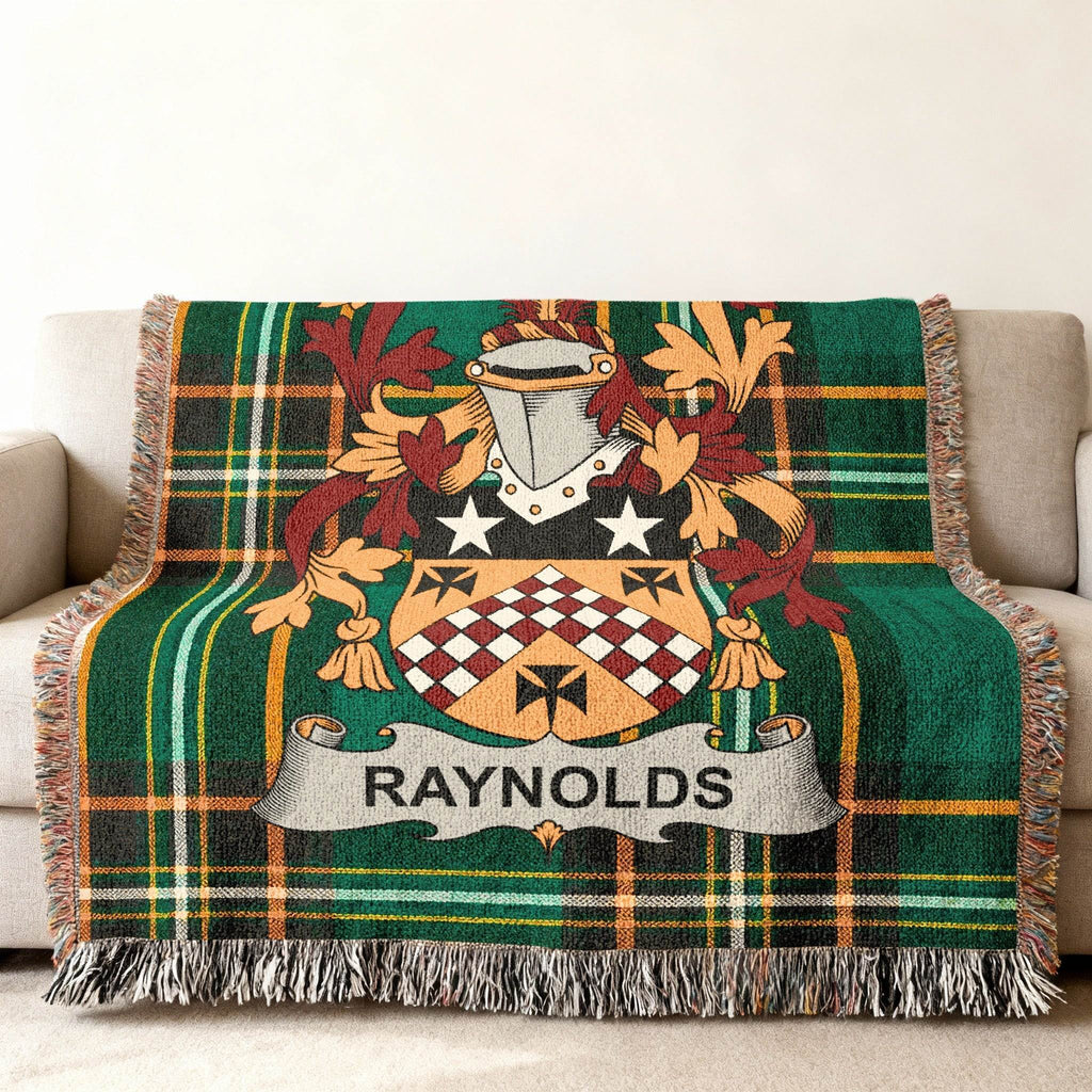 Tartan throw blanket with a crest and the name "RAYNOLDS" on a sofa.