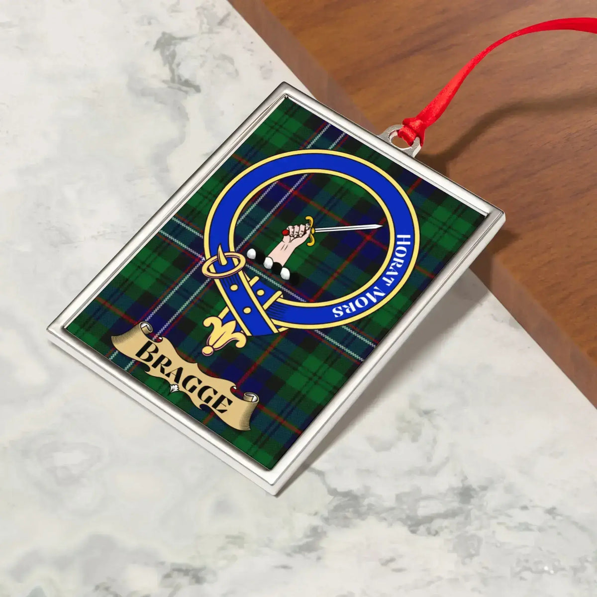 Bragge ornament hanging from a Christmas tree branch by its satin ribbon