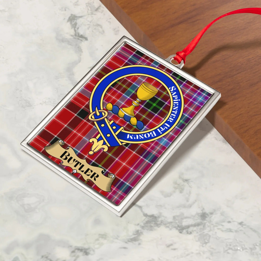Butler ornament hanging from a Christmas tree branch by its satin ribbon