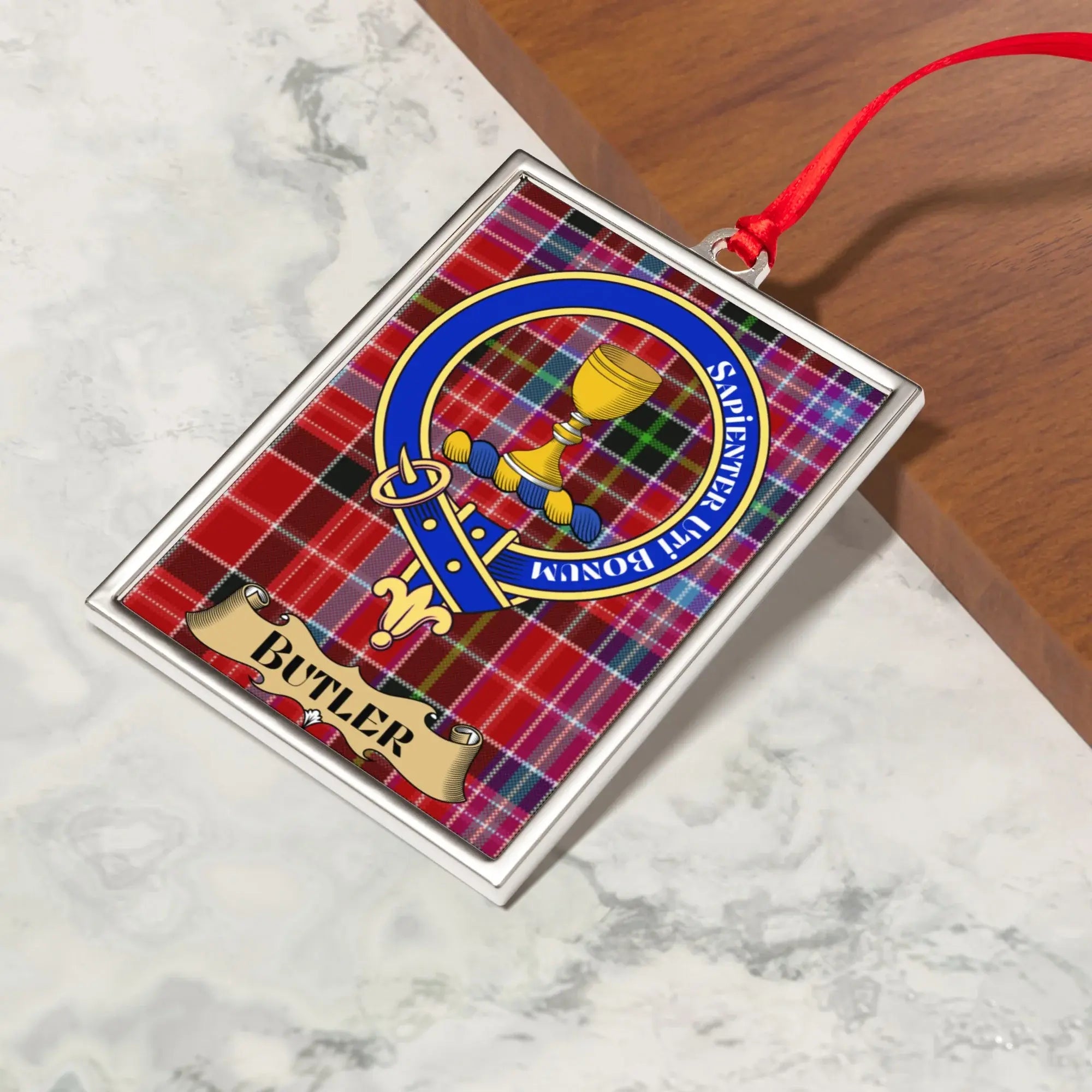 Butler ornament hanging from a Christmas tree branch by its satin ribbon