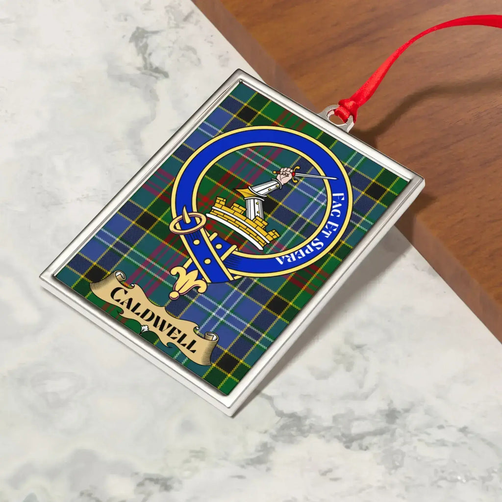 Caldwell ornament hanging from a Christmas tree branch by its satin ribbon