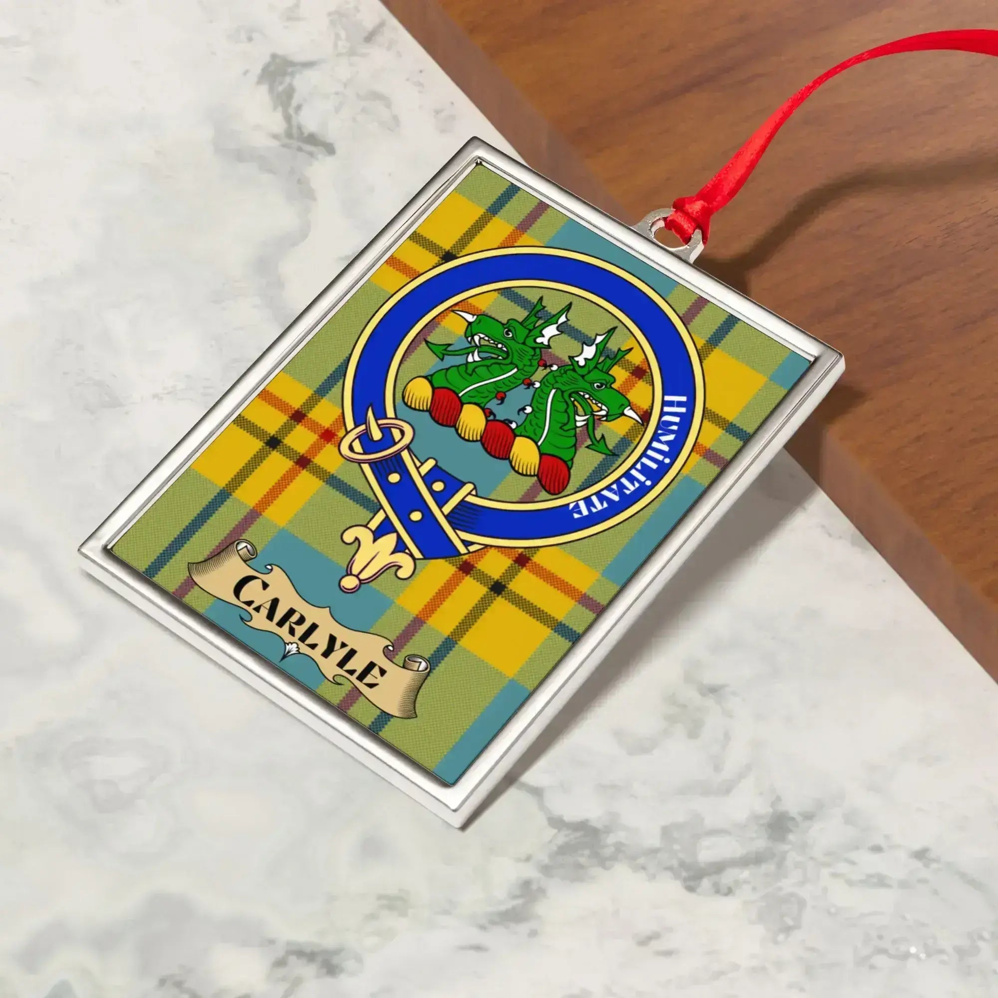 Carlyle ornament hanging from a Christmas tree branch by its satin ribbon
