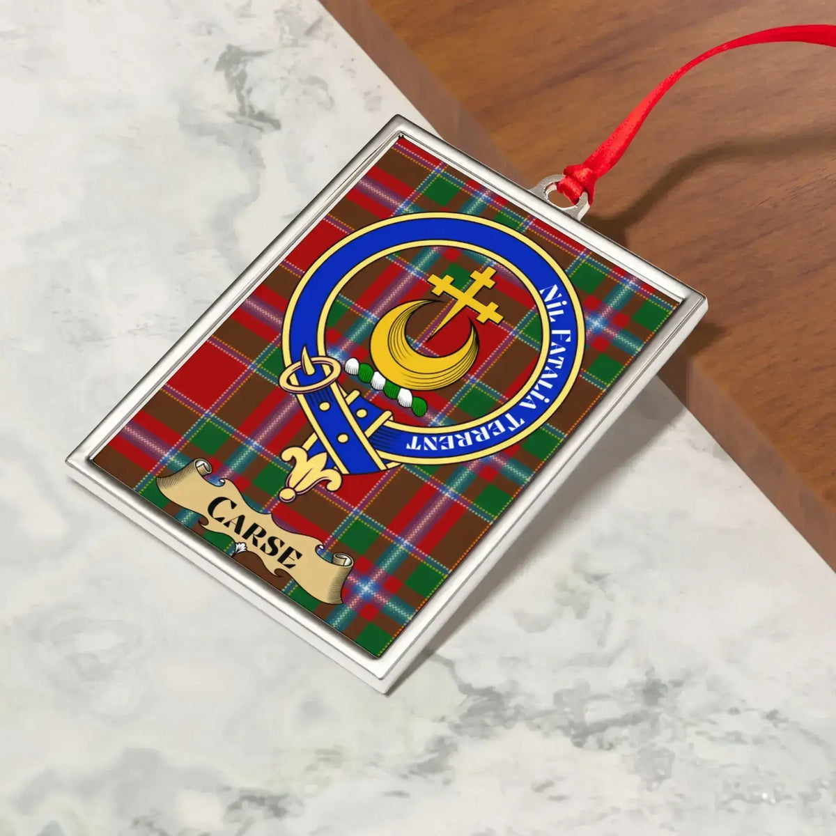 Carse ornament hanging from a Christmas tree branch by its satin ribbon
