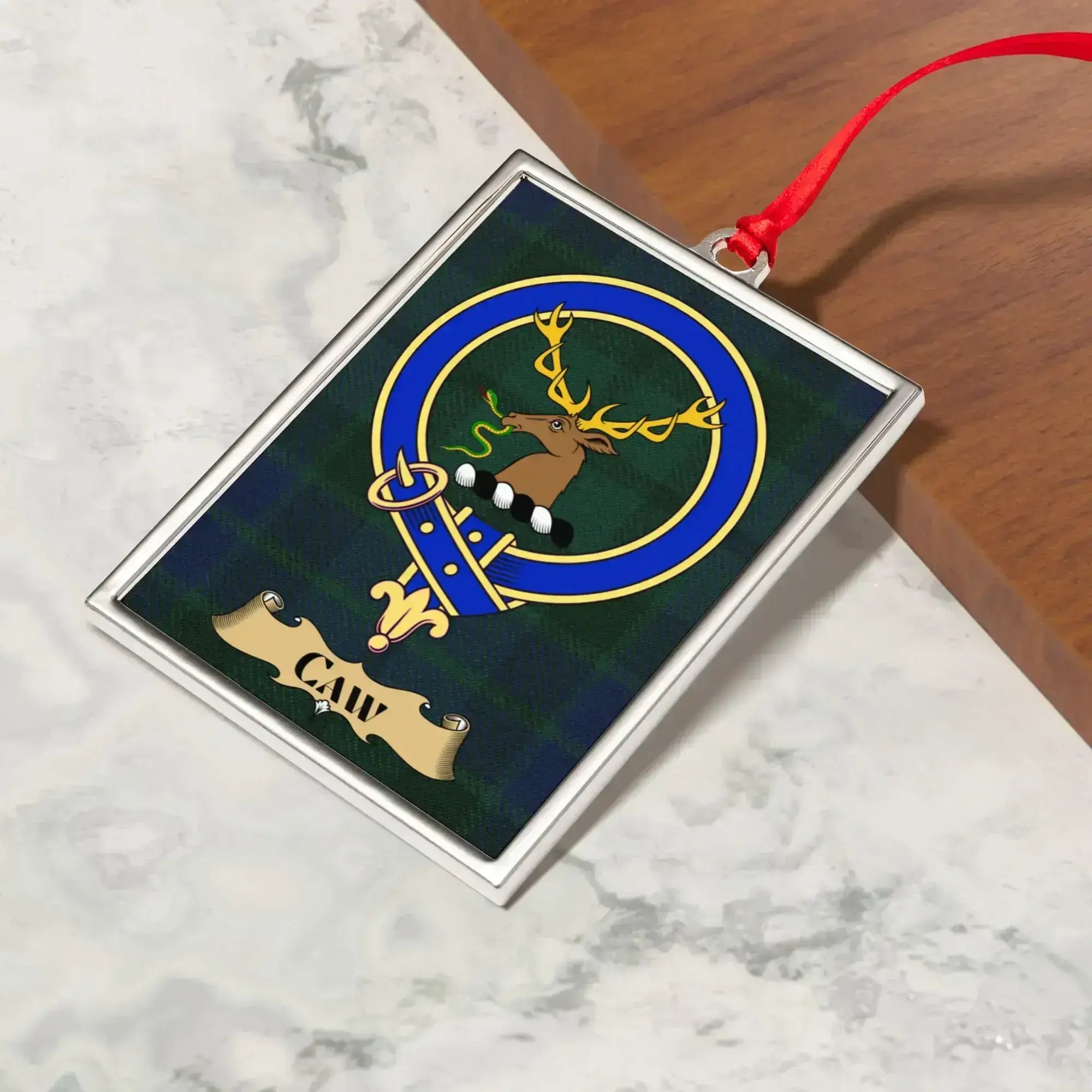 Caw ornament hanging from a Christmas tree branch by its satin ribbon