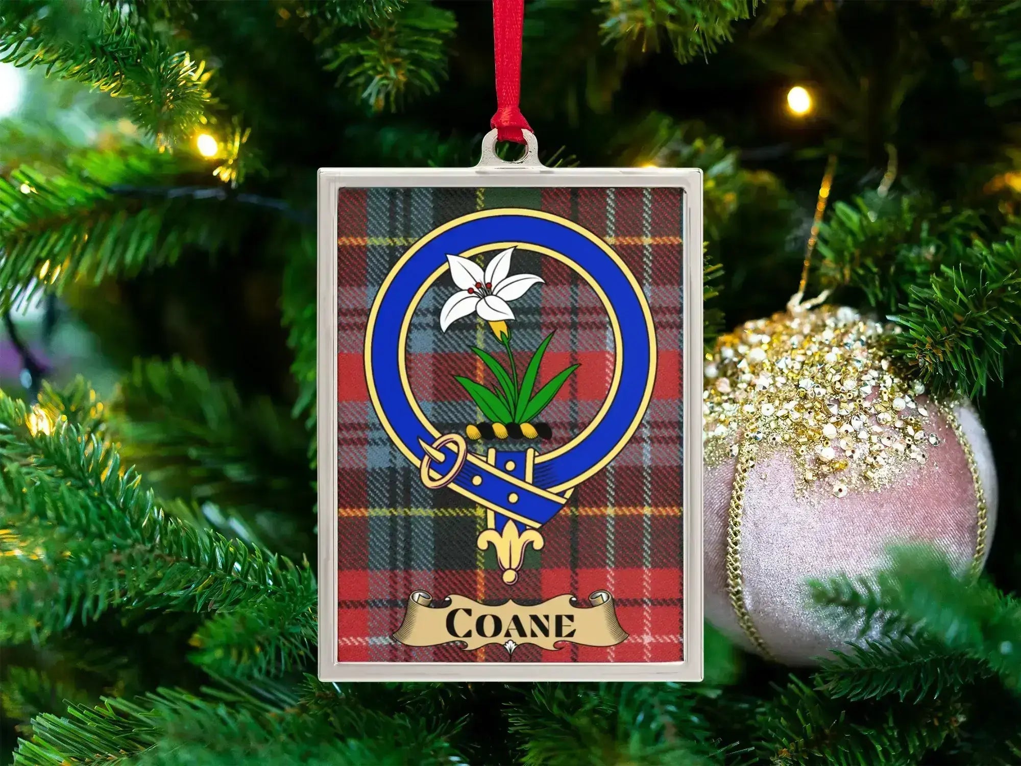 Coane clan crest Christmas ornament in a silver frame on a tartan background