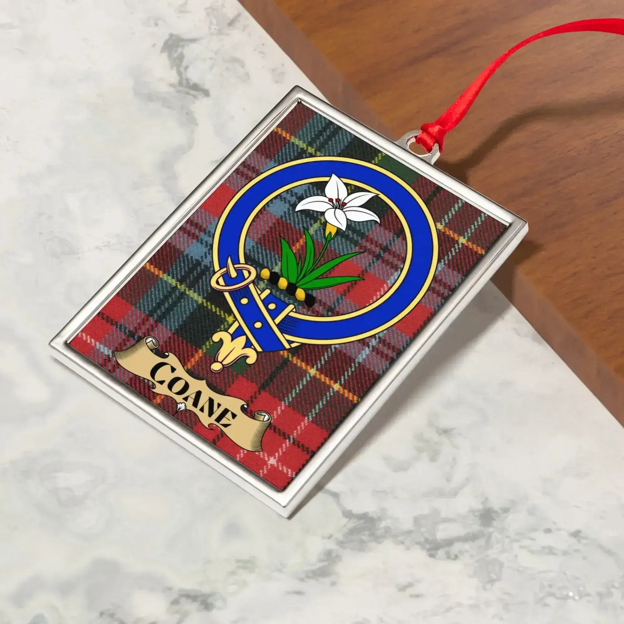 Coane ornament hanging from a Christmas tree branch by its satin ribbon
