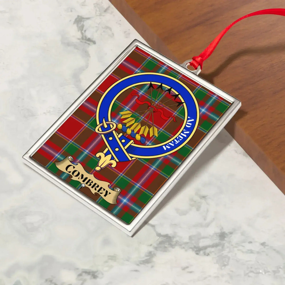 Combrey ornament hanging from a Christmas tree branch by its satin ribbon