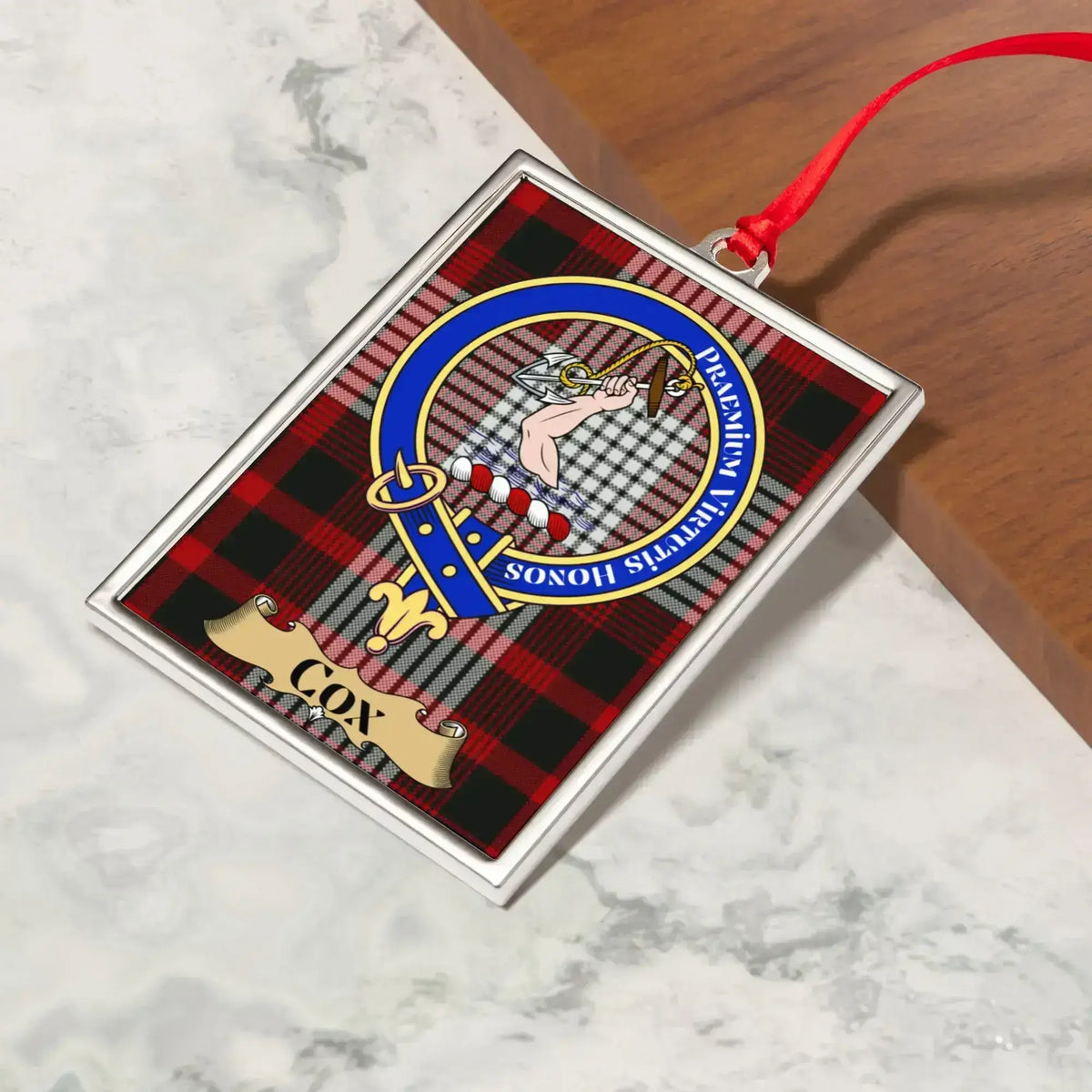 Cox ornament hanging from a Christmas tree branch by its satin ribbon