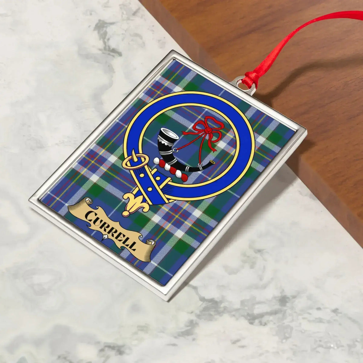 Currell ornament hanging from a Christmas tree branch by its satin ribbon