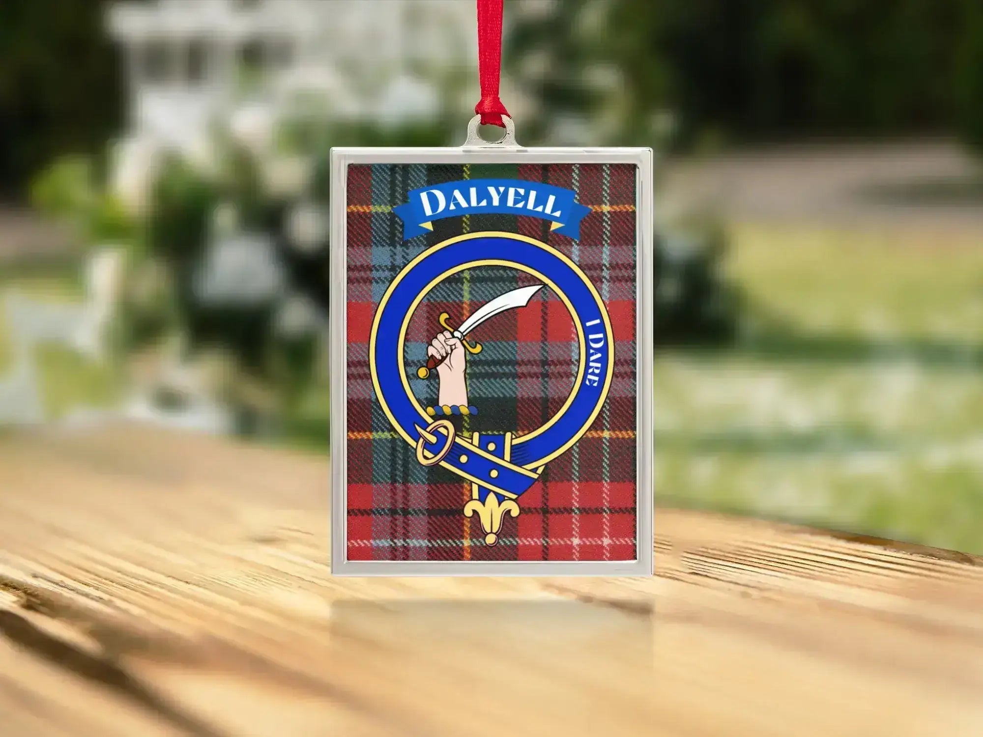 Close-up of the Dalyell family crest on a polished silver-frame metal ornament