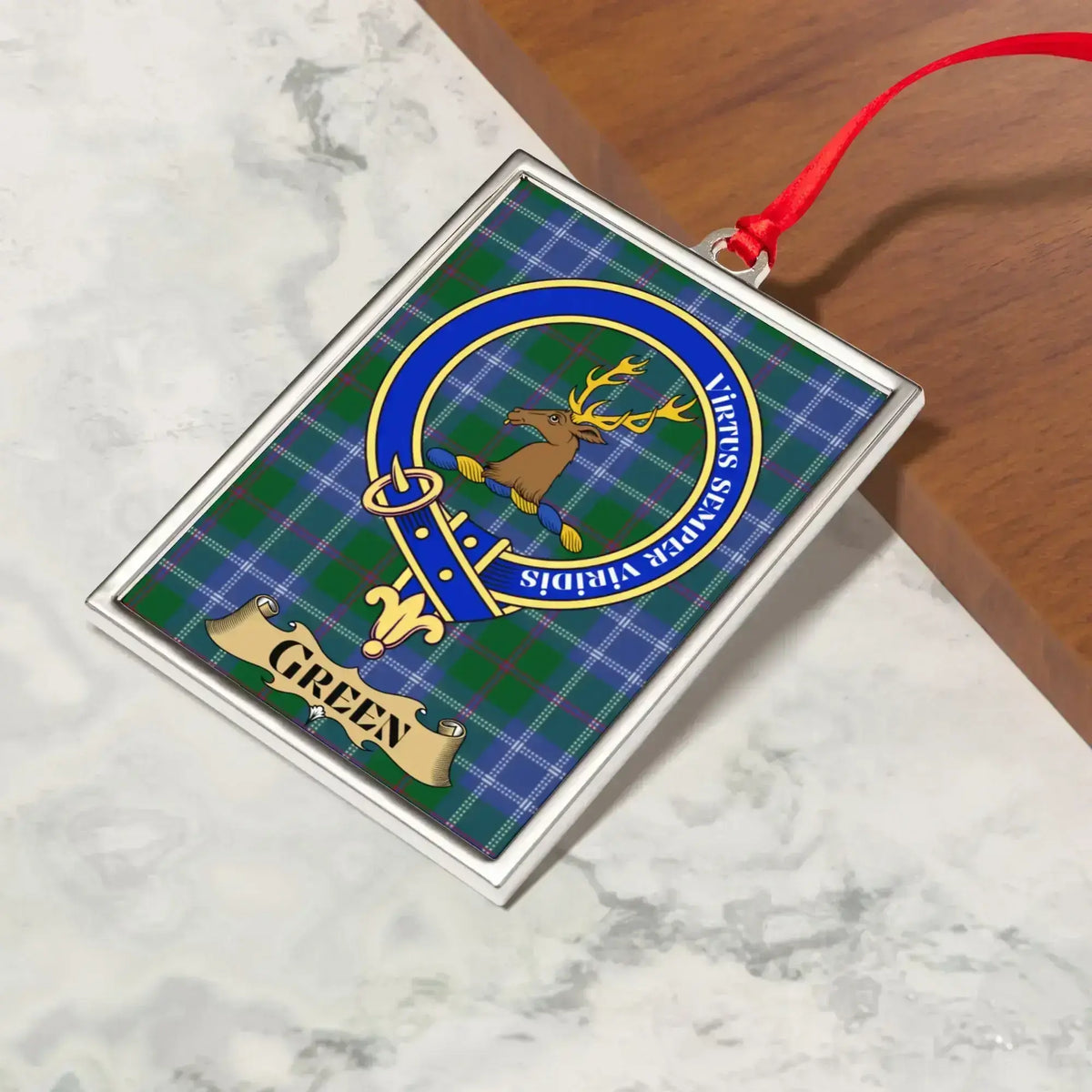 Green ornament hanging from a Christmas tree branch by its satin ribbon