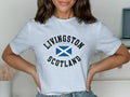 Livingston Scotland t-shirt — lifestyle shot showing printed design, light blue, white, sand options