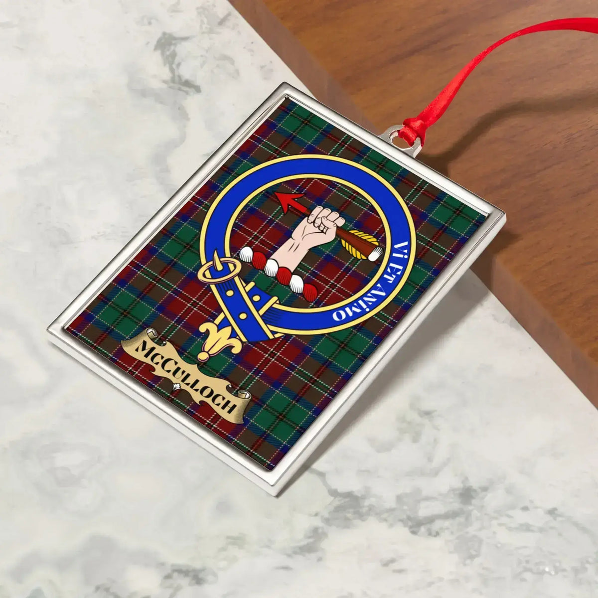 McCulloch ornament hanging from a Christmas tree branch by its satin ribbon
