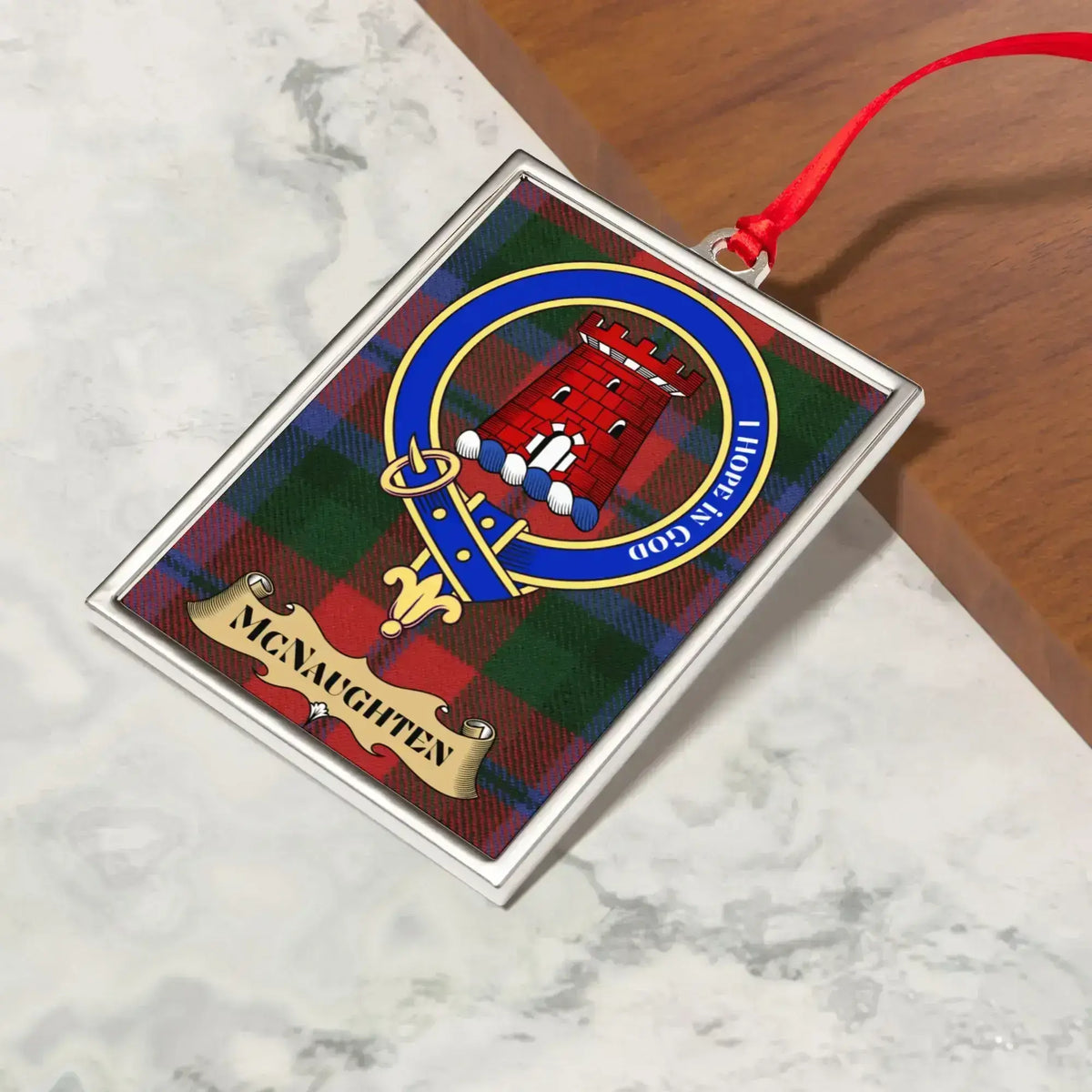 McNaughten ornament hanging from a Christmas tree branch by its satin ribbon