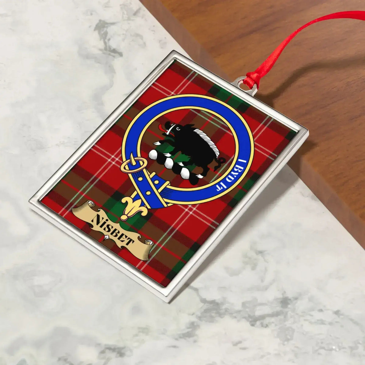 Nisbet ornament hanging from a Christmas tree branch by its satin ribbon