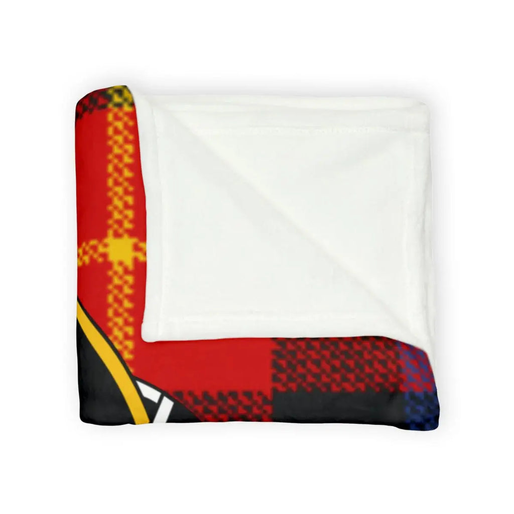 Primrose tartan throw blanket on sofa — red and black plaid with clan crest