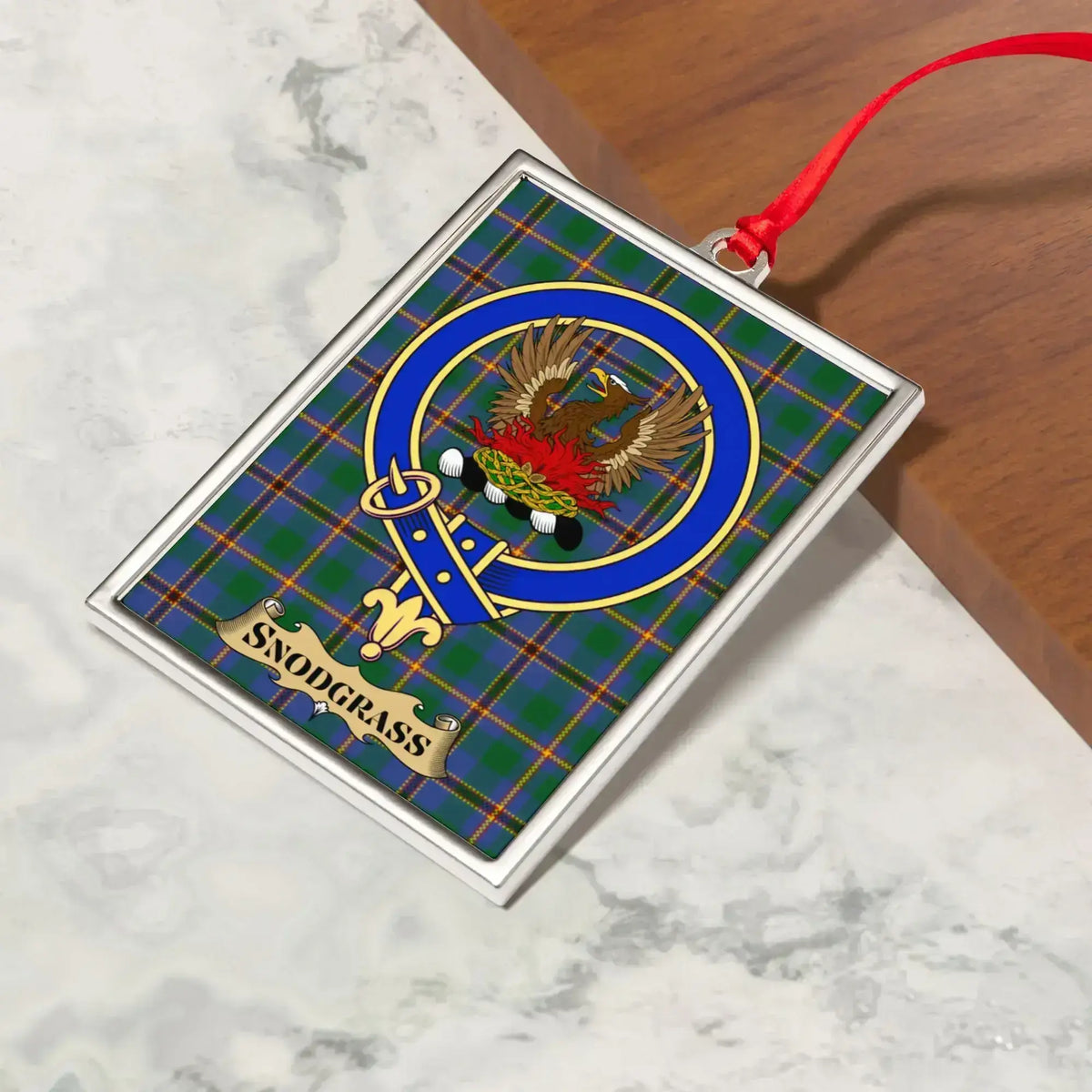 Snodgrass ornament hanging from a Christmas tree branch by its satin ribbon