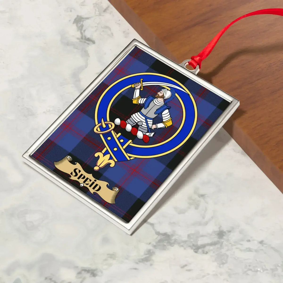 Speid ornament hanging from a Christmas tree branch by its satin ribbon