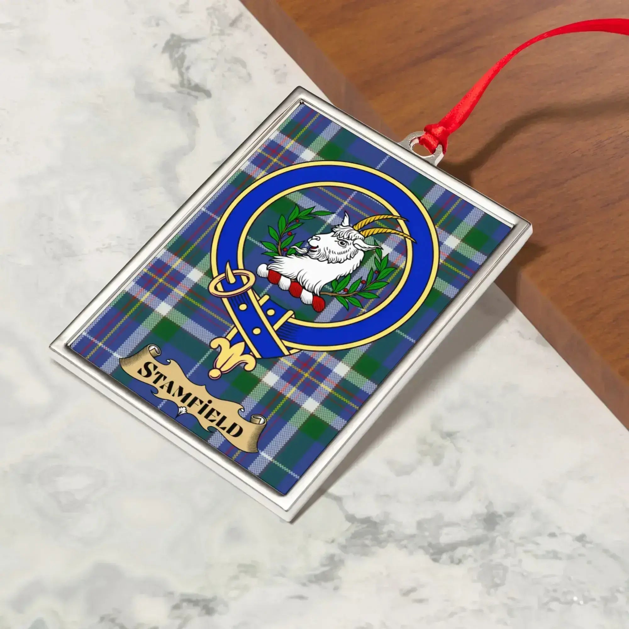 Stamfield ornament hanging from a Christmas tree branch by its satin ribbon