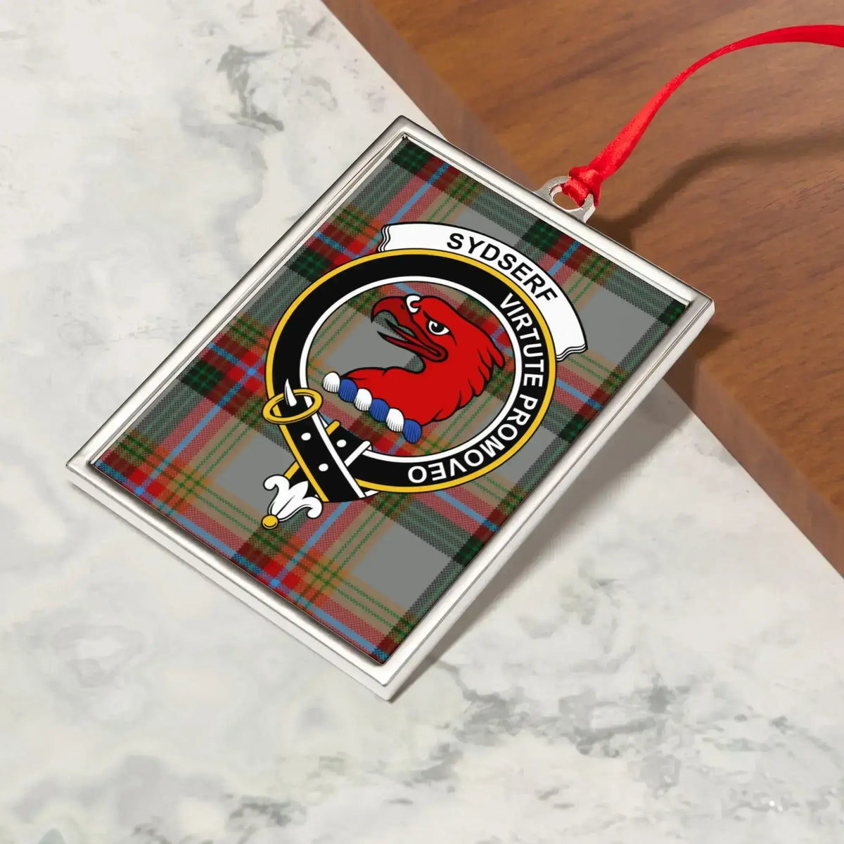 Sydserf ornament hanging from a Christmas tree branch by its satin ribbon