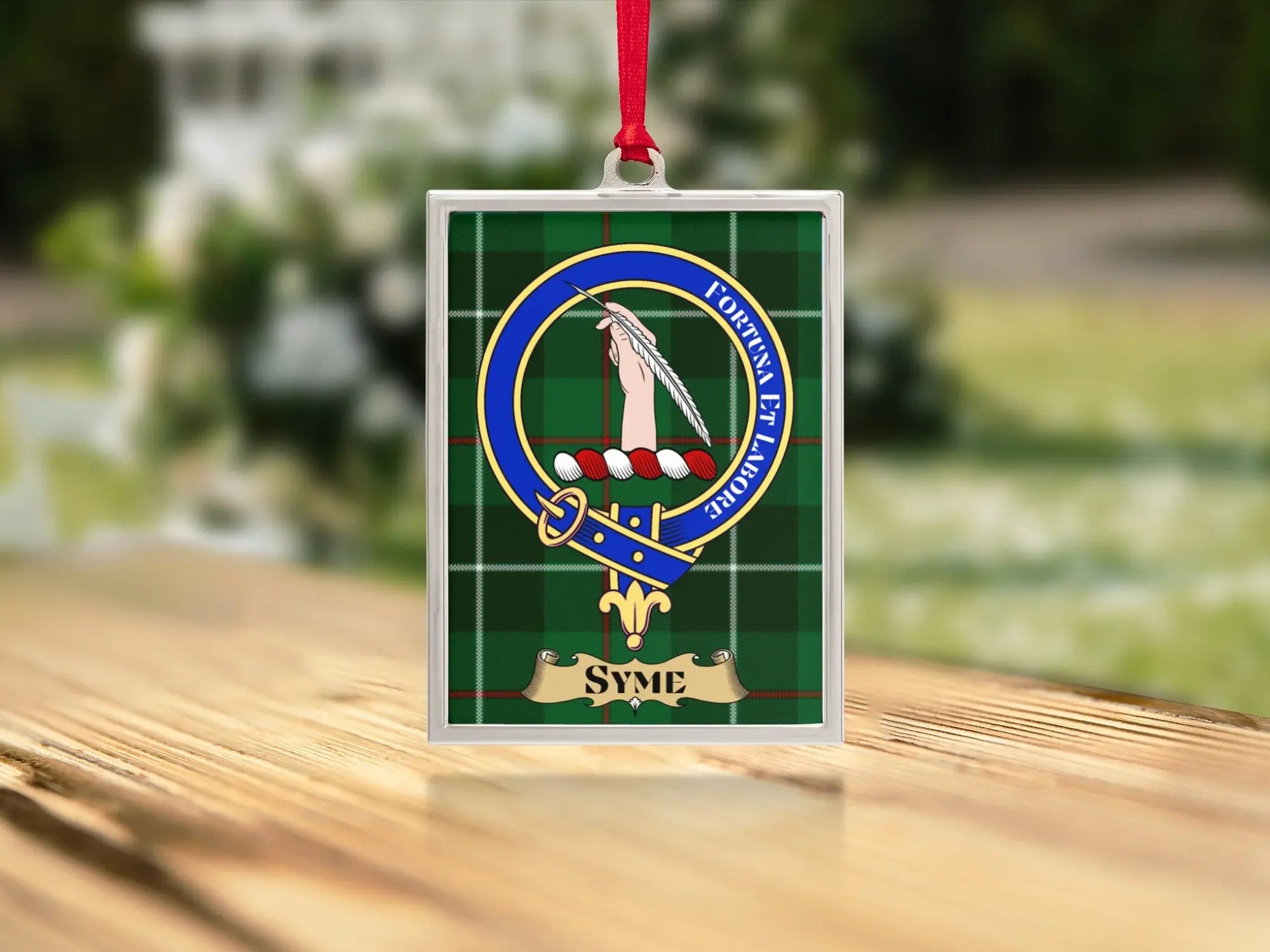 Close-up of the Syme family crest on a polished silver-frame metal ornament