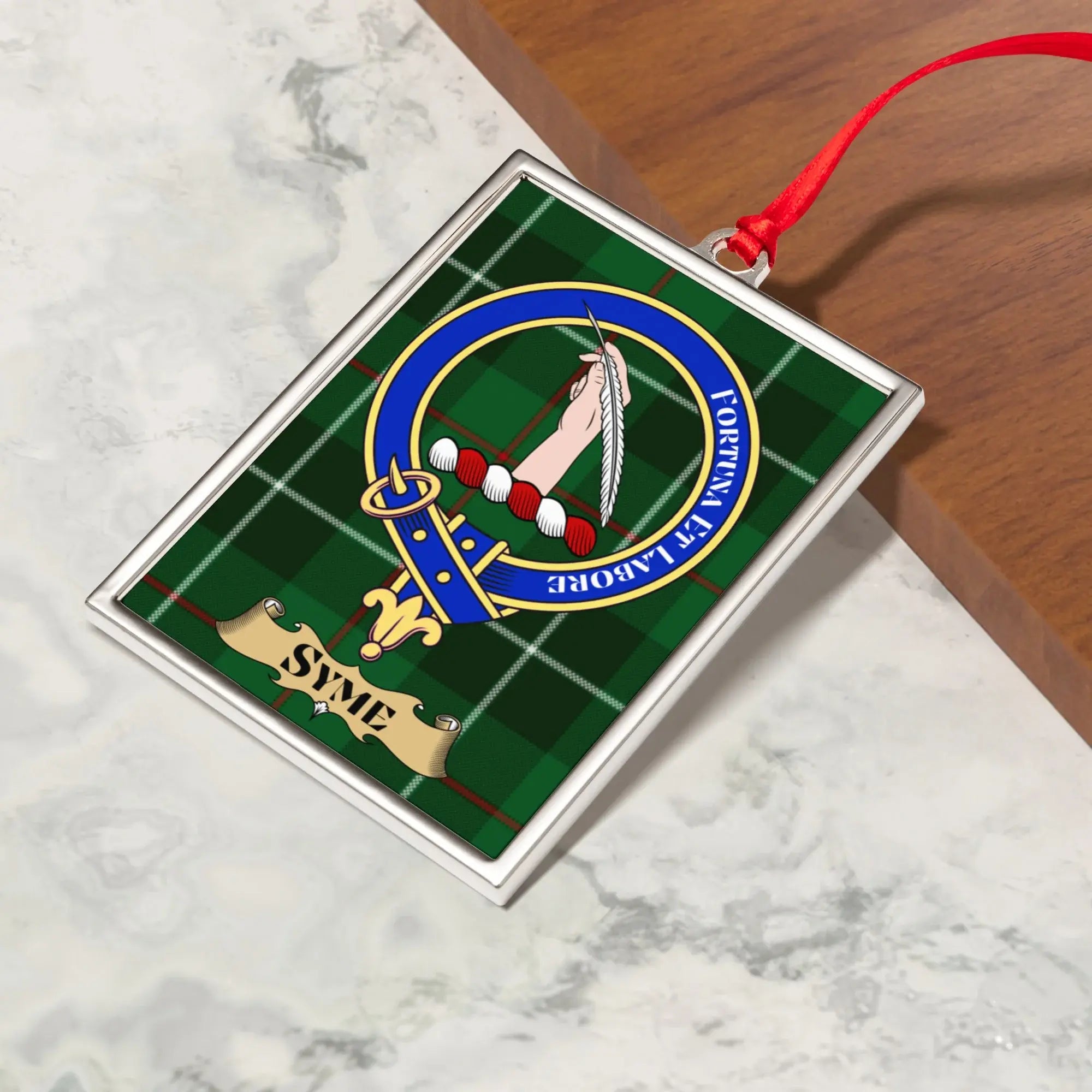 Syme ornament hanging from a Christmas tree branch by its satin ribbon