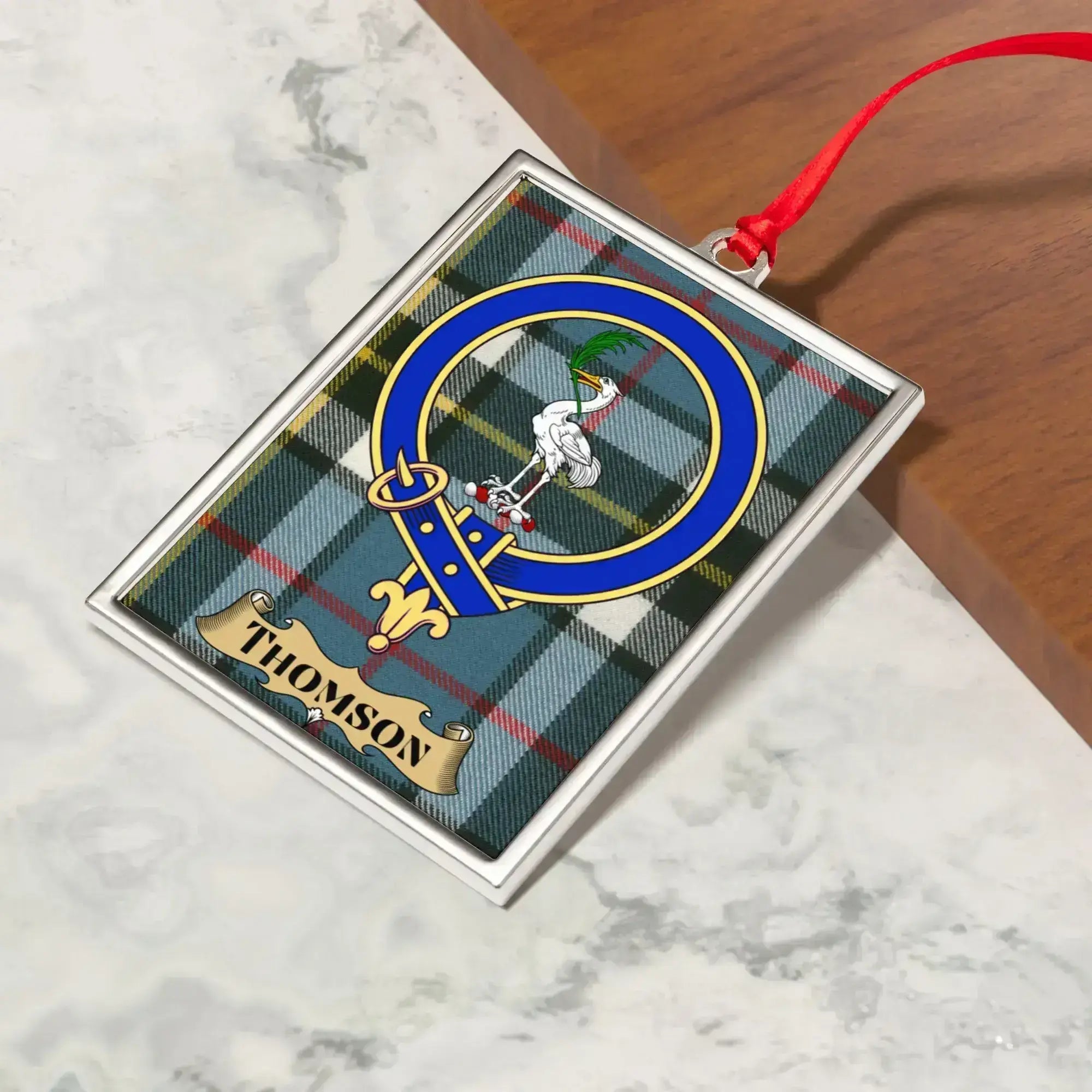 Thomson ornament hanging from a Christmas tree branch by its satin ribbon