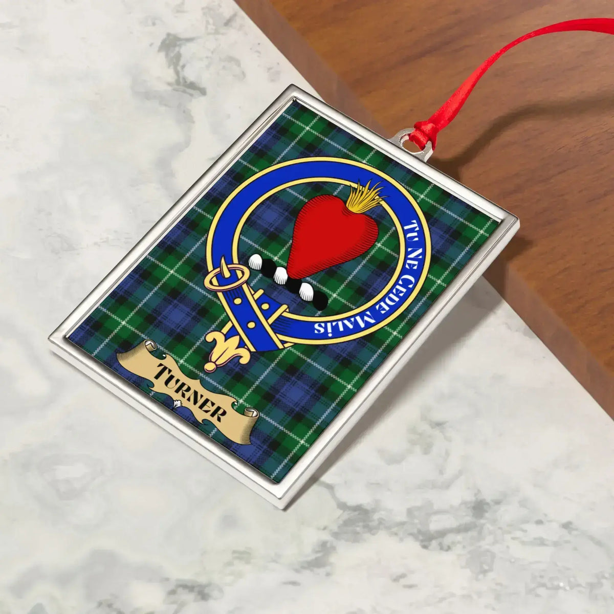 Turner ornament hanging from a Christmas tree branch by its satin ribbon