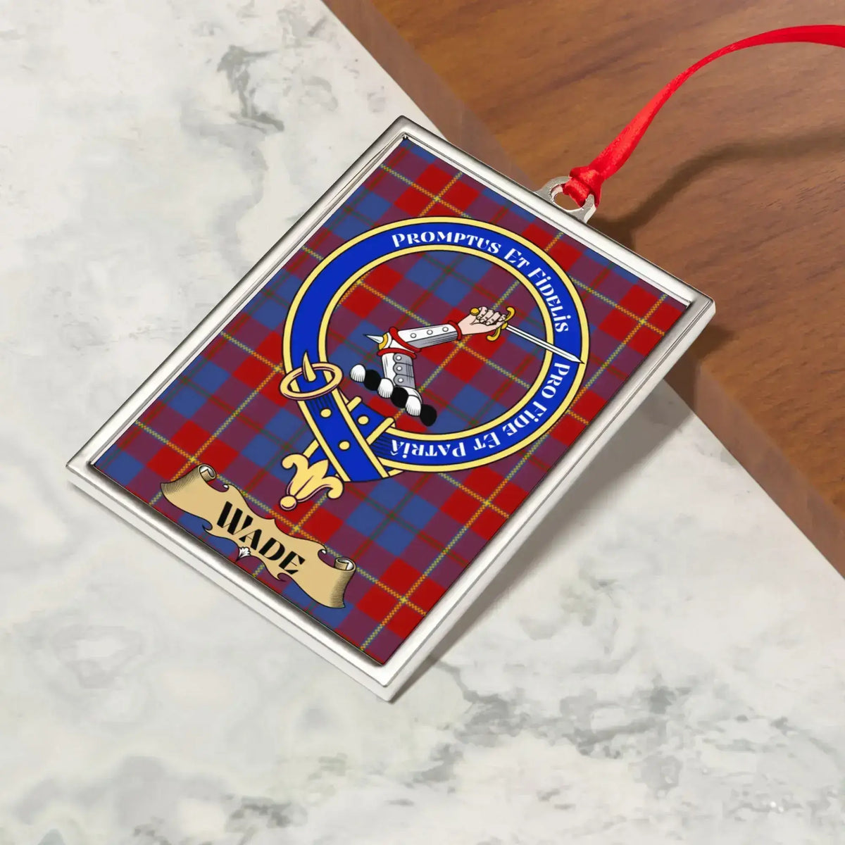Wade ornament hanging from a Christmas tree branch by its satin ribbon