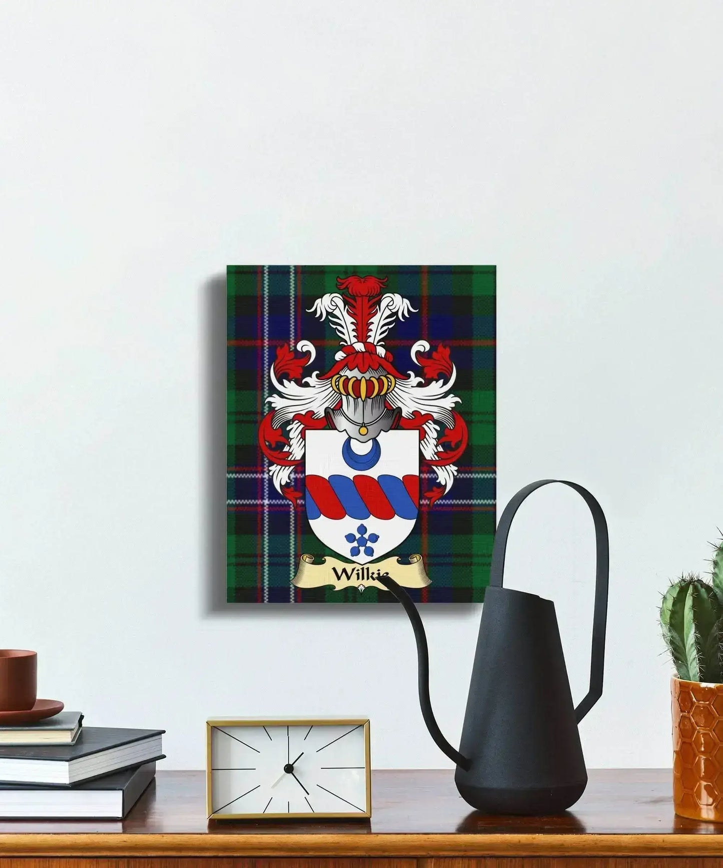 Wilkie clan coat of arms canvas with tartan background hanging on white wall above wooden shelf