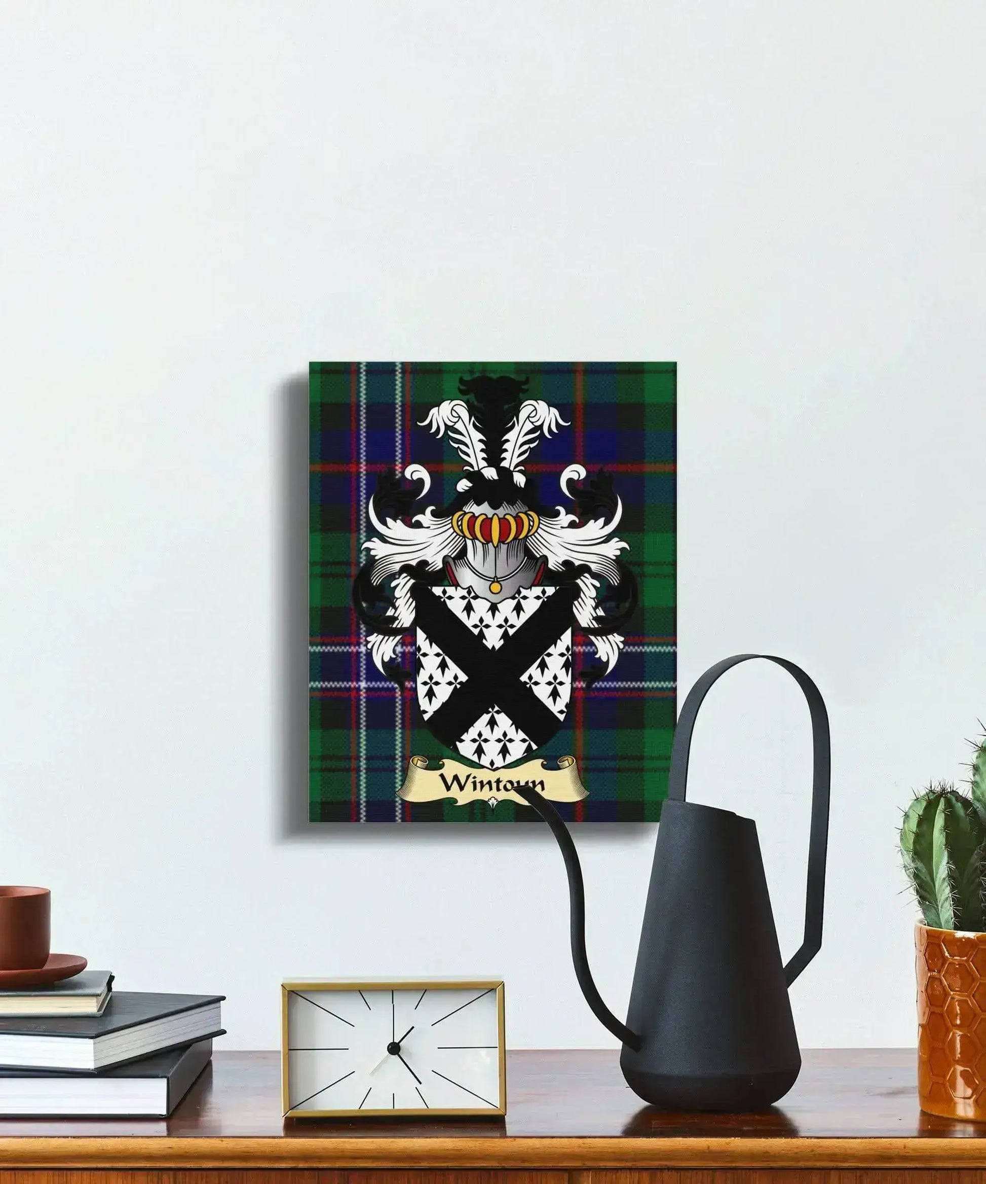 Wintoun clan coat of arms on tartan canvas print hanging above wooden table with books, clock, black pitcher, and cactus